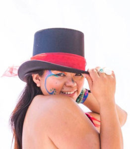 arts facilitator diia bourke appointed 2019. wearing top hat with red band.smiling, with painted face.
