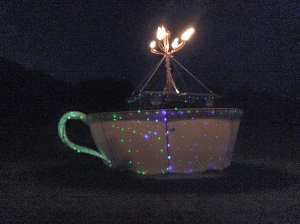 A giant mobile teacup shooting flames at night.
