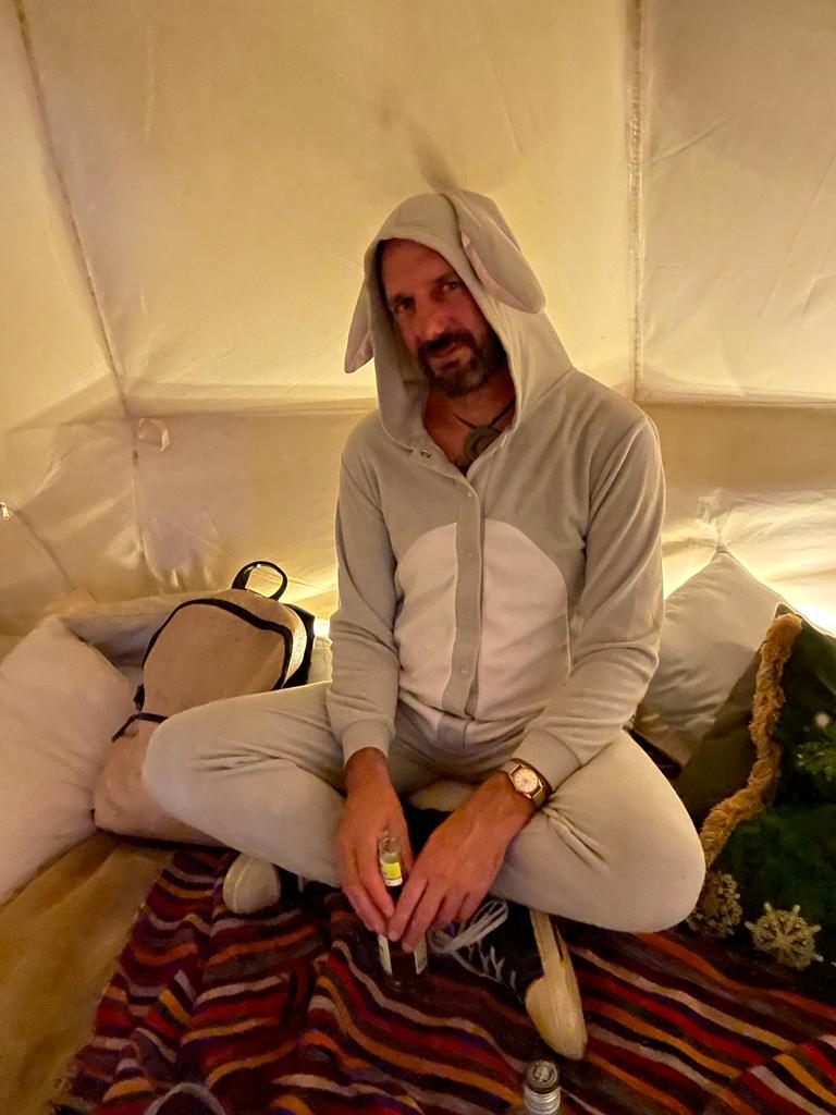 Floyd, sitting crosslegged in a tent, dressed in a grey bunny onesie
