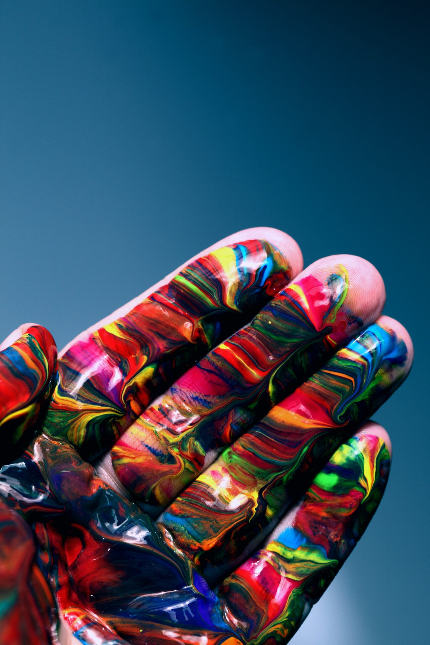 A close up of the palm of a hand covered in swirls of brightly coloured paint