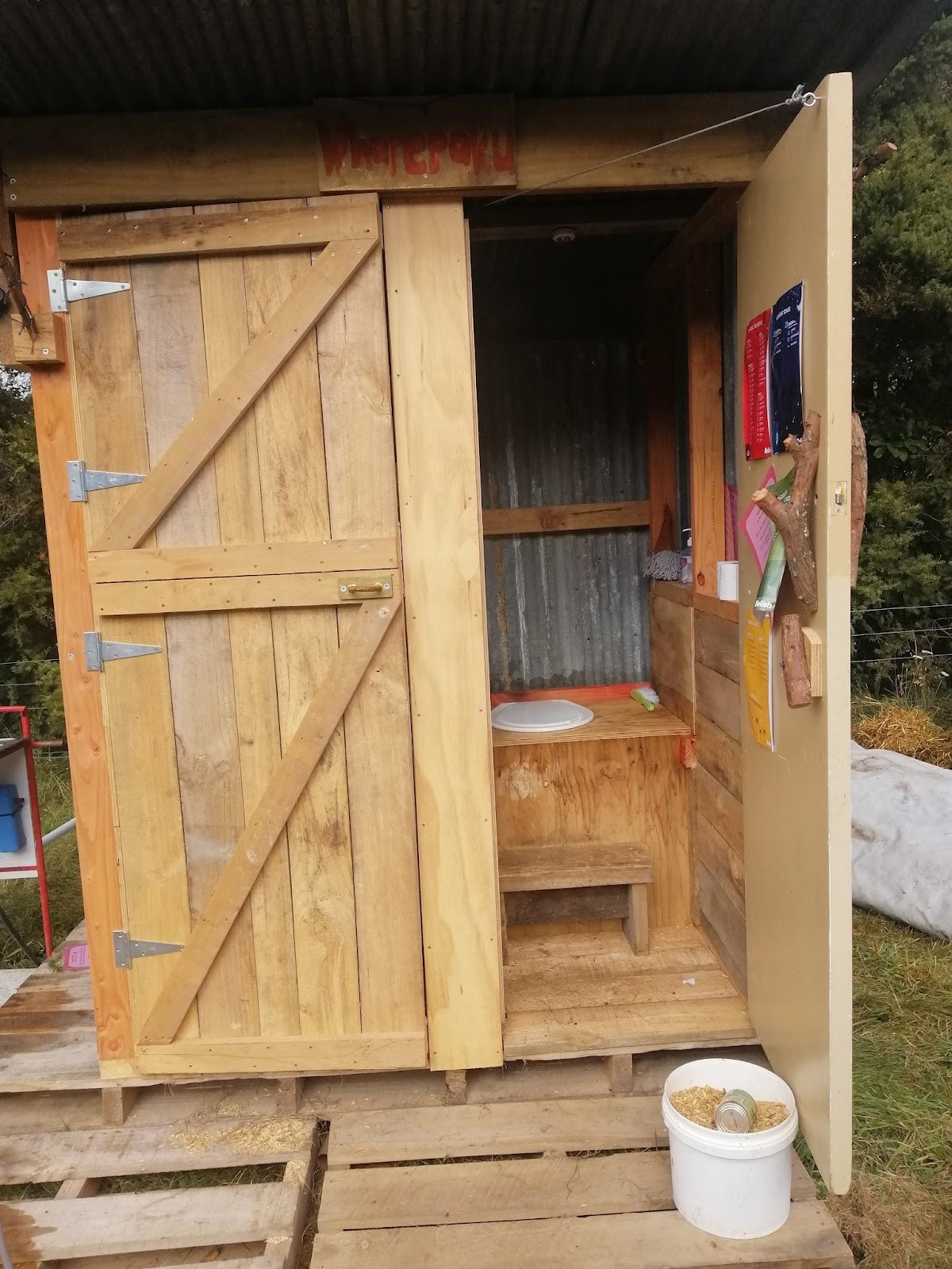 A clean, wooden, compostable toilet with an open door