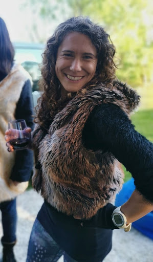 Jax posing with a huge smile in a furry vest with a wine in hand