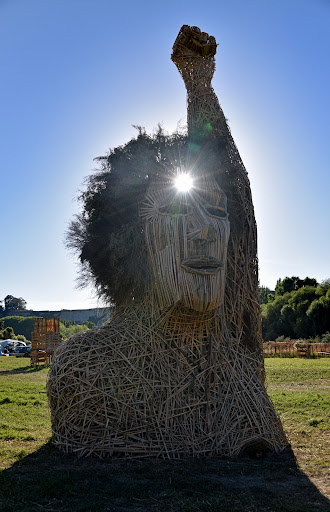 A wooden structure (the Effigy) that resembles the head and shoulders of a person with their fist in the air, with the sun shining through a spot on the forehead