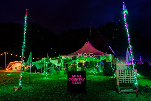 Mint Country Club sits lit up in all it's green glory against a dark night sky