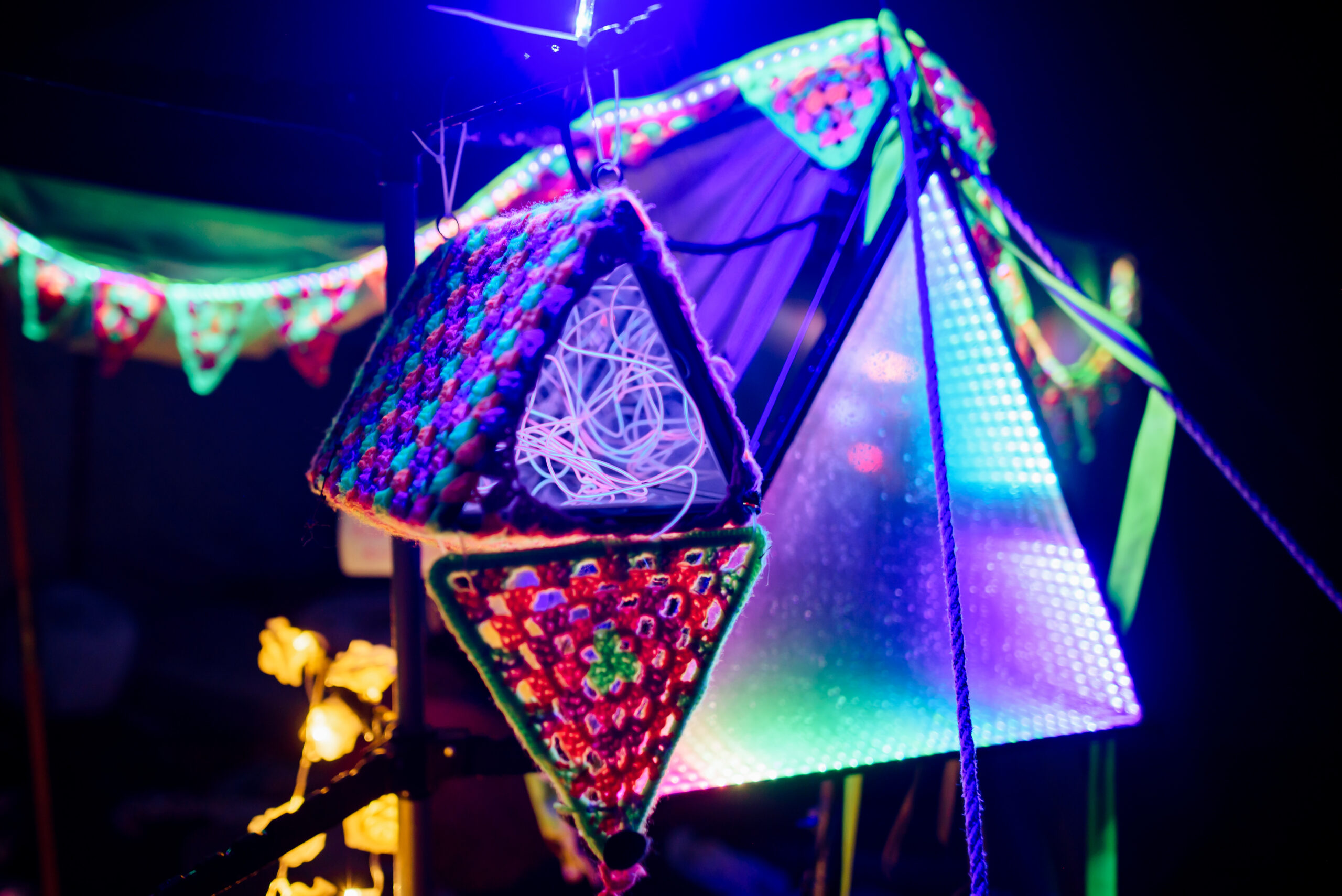 a small triangle filled with lights sits in front of a large infinity triangle