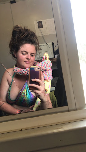 A person in a sparkly bikini wearing a cuddly soft toy is taking a selfie in a mirror