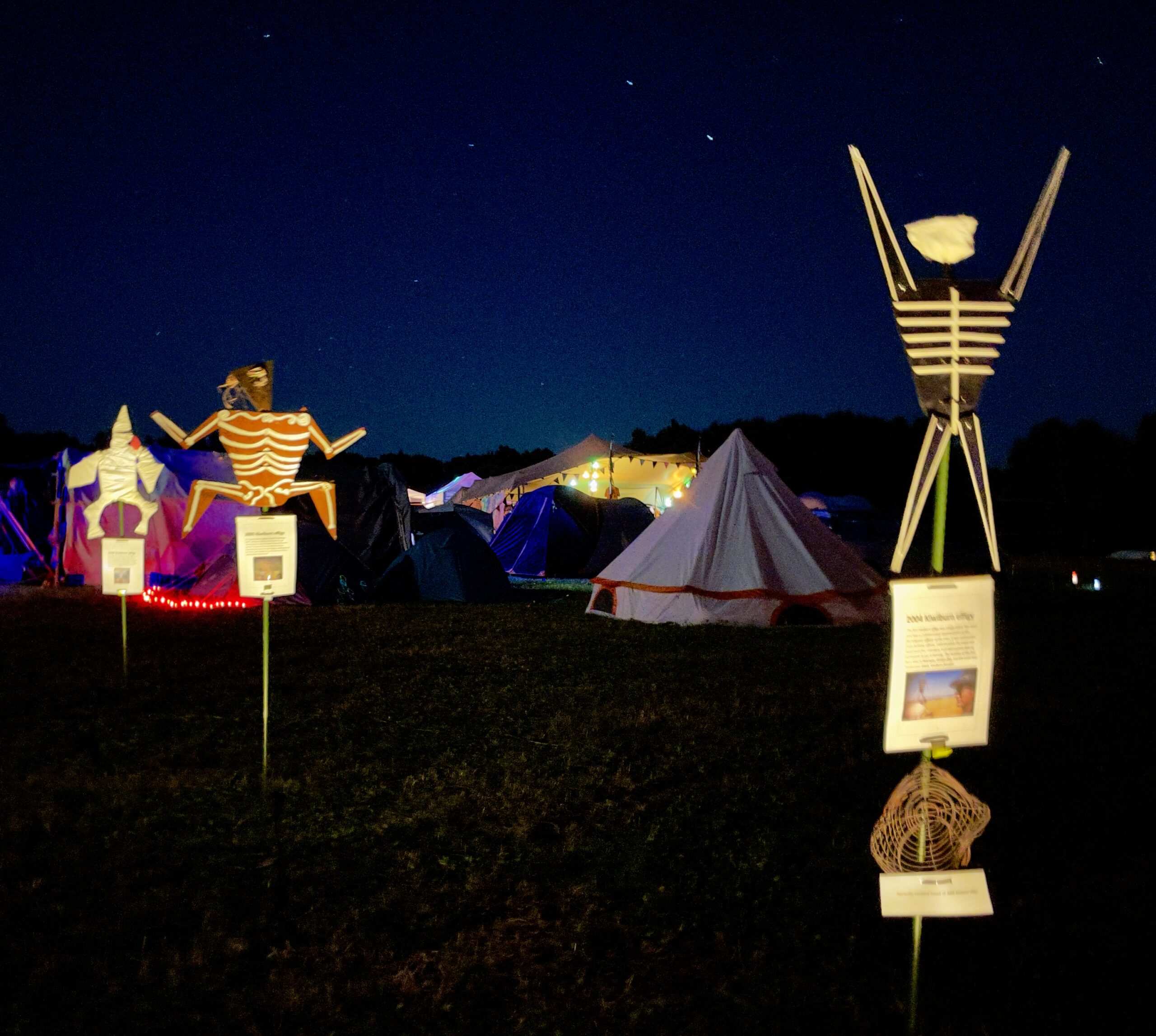 Artwork of previous effigy's stands lit up against a dark camp backdrop
