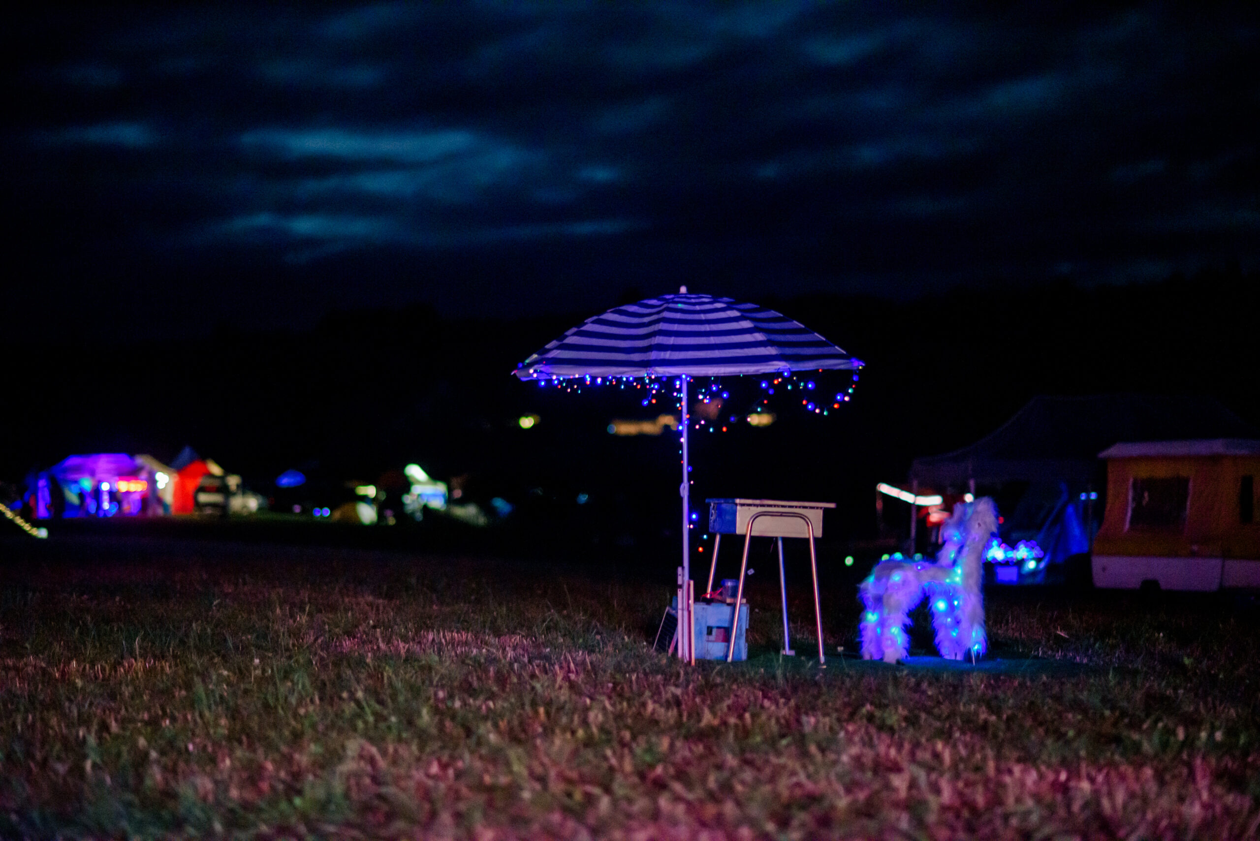 A bunch of LED items including an umbrella sit lit up against a black night