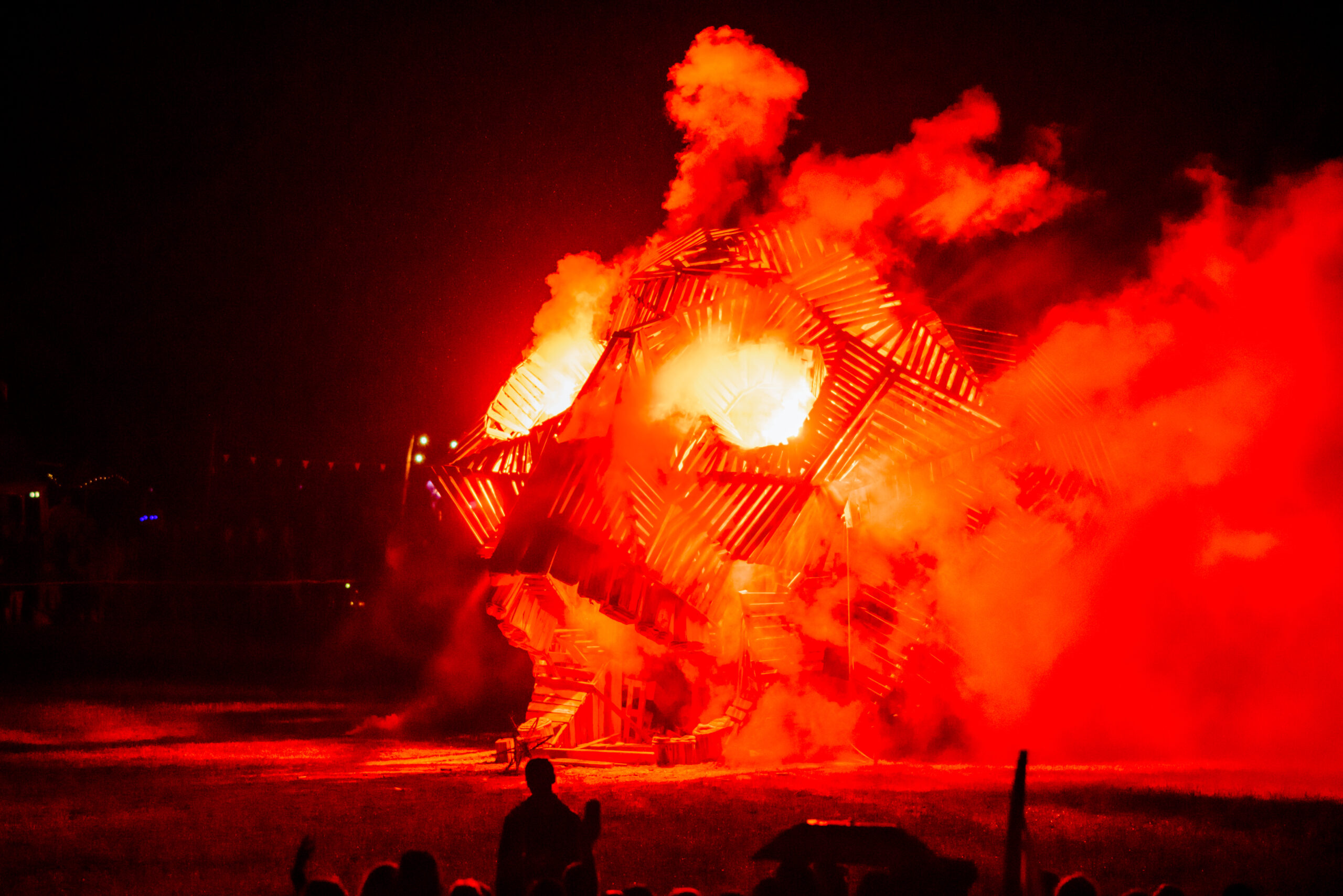 A skull effigy is engulfed in bright orange and yellow flames