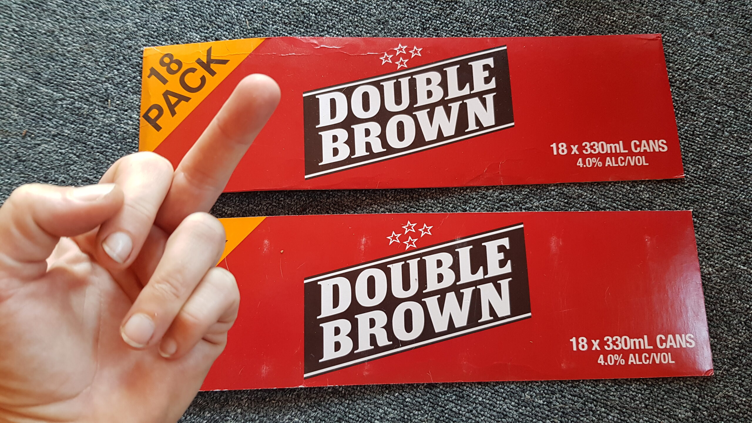 a hand is pulling the middle finger at a couple of Double Brown box sides