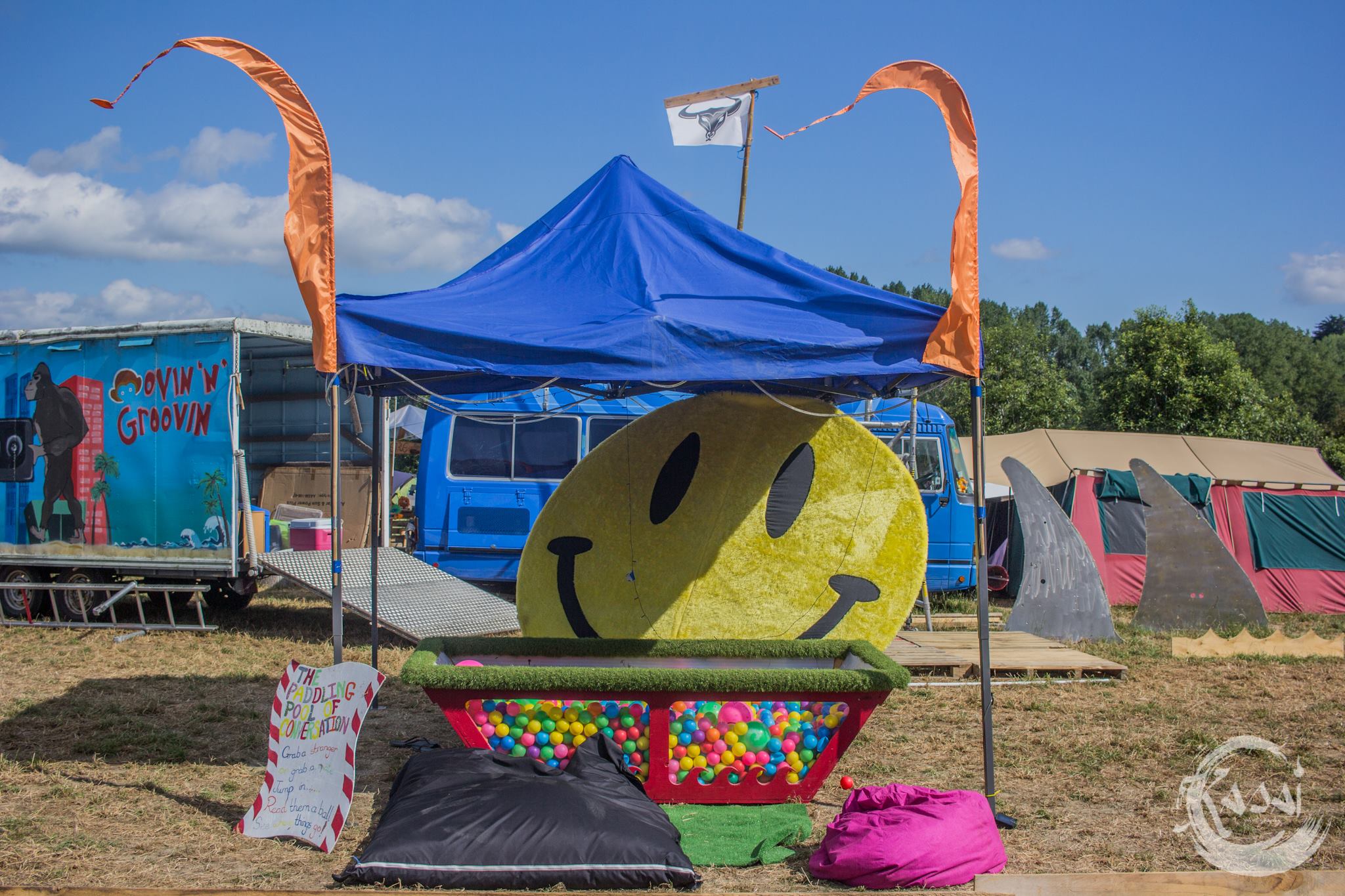A blue gazebo houses a ball pit and a giant yellow smiley face