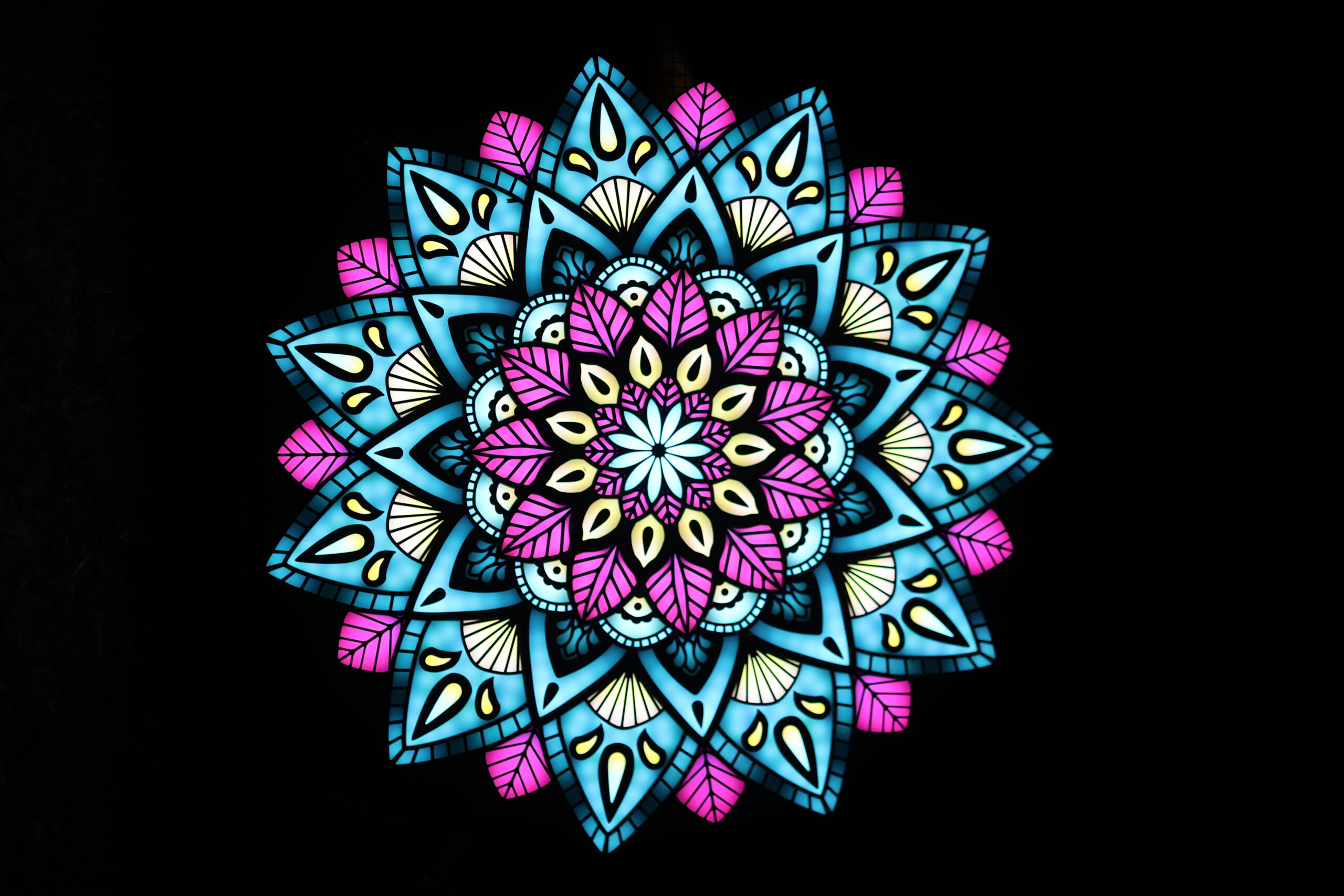 A colourful LED mandala is brightly lit against a dark night