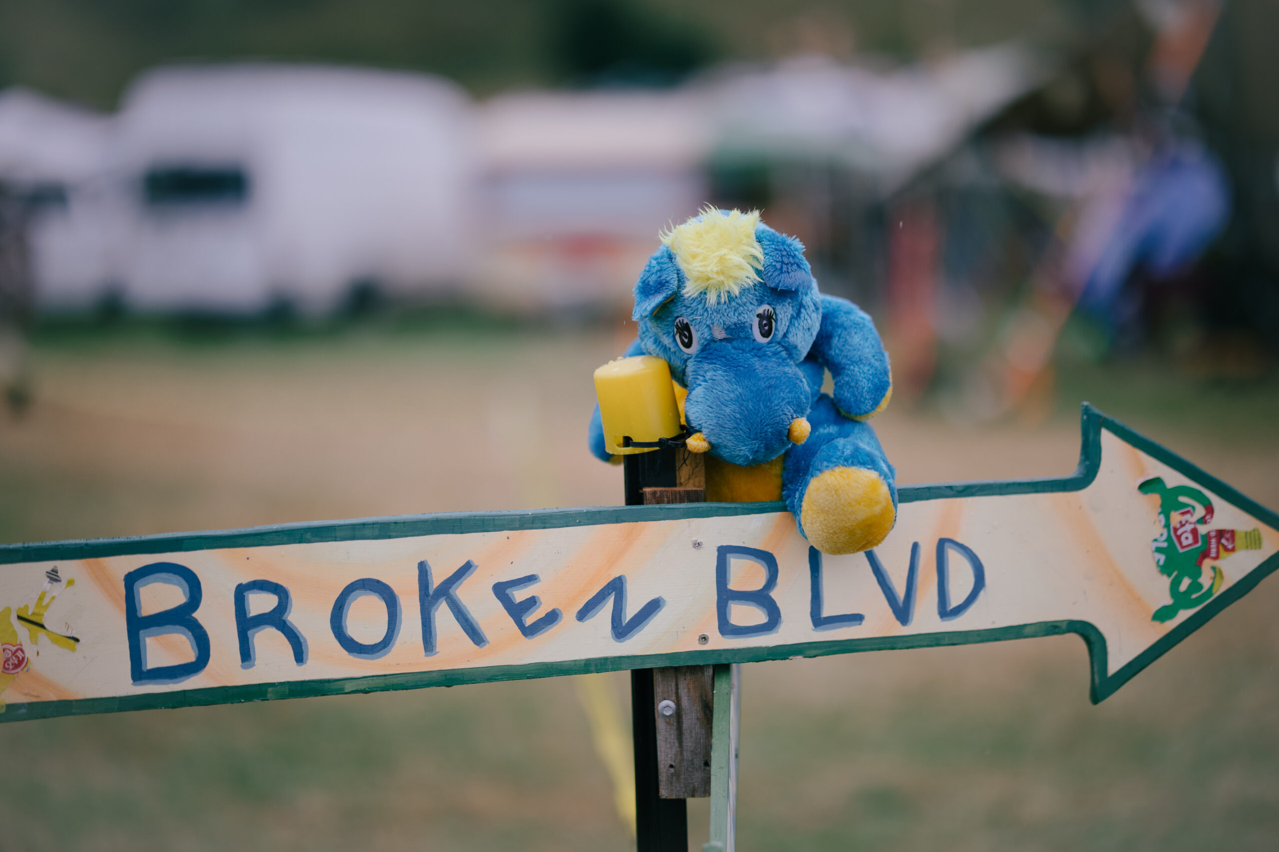 A kiwiburn street-sign titled 'Broken Boulevard' with a blue stuffed monster sitting on it